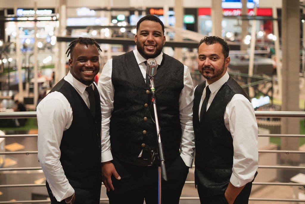 Ivirson e os dois colegas de banda, de colete e gravata, a sorrir para a câmara depois do concerto